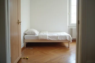 Petite chambre avec lit simple et parquet en bois illustrant les critères de surface minimale réglementaire